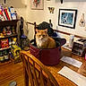 cat, orange_cat, bag, wooden_table, chair, toaster, vacuum_cleaner, food_packages, books, wall_art, kitchen, dining_room, wooden_floor, envelope, paper_towel, shelf, decorations, cupboard, household_items, pet