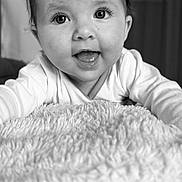 Lya a rejoint le concours — aidez-le/la à gagner de superbes lots ! baby, infant, face, eyes, smile, tongue, blanket, soft_texture, close_up, black_and_white, cute, child, portrait, happy, indoors, young, expression, clothing, head, person