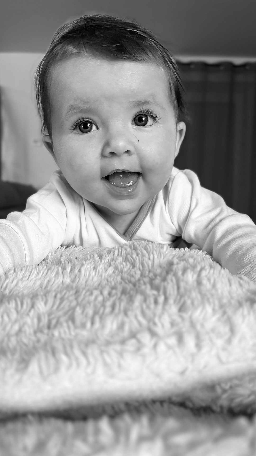 Lya a rejoint le concours — aidez-le/la à gagner de superbes lots ! baby, infant, face, eyes, smile, tongue, blanket, soft_texture, close_up, black_and_white, cute, child, portrait, happy, indoors, young, expression, clothing, head, person