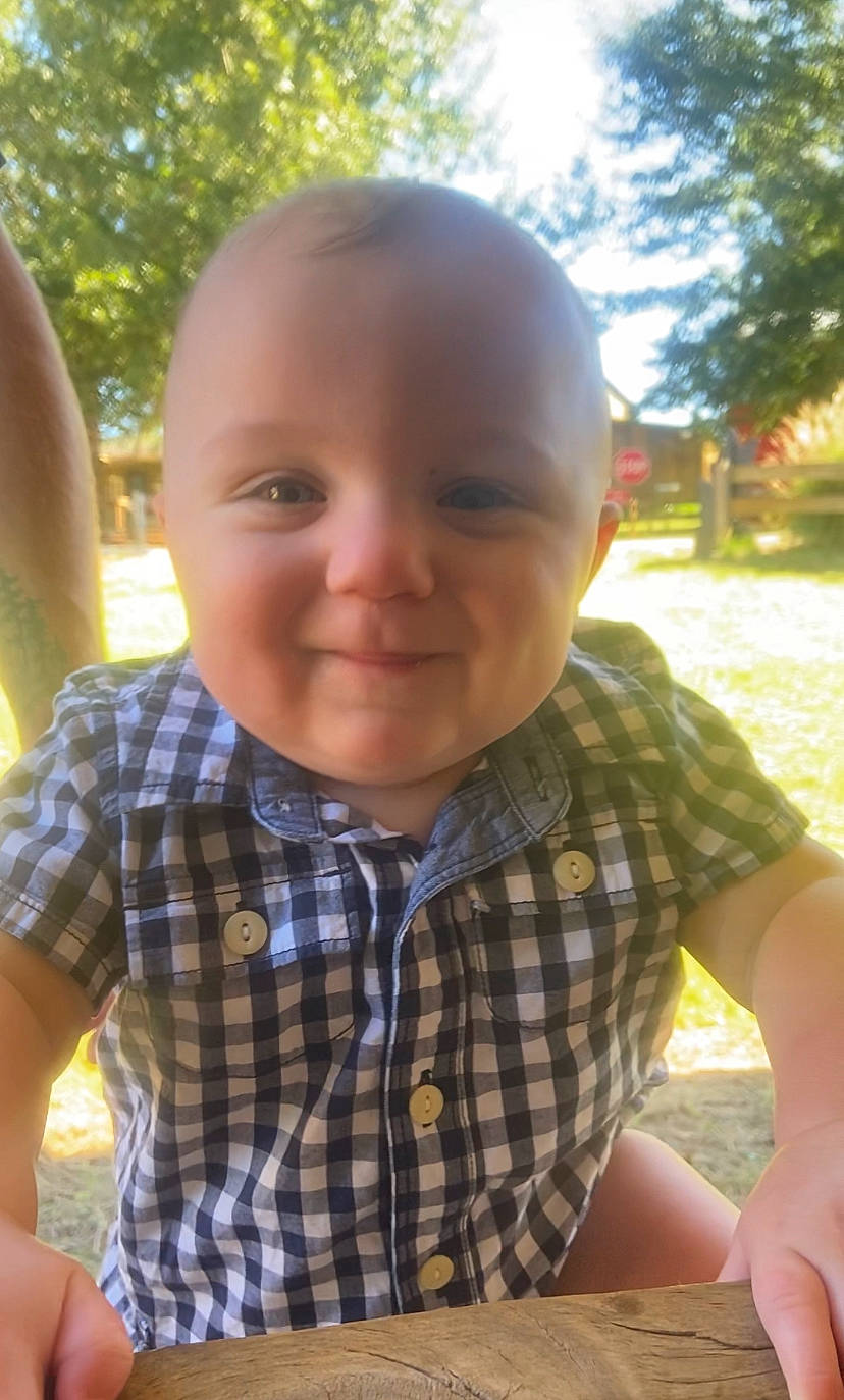 Tyson is registered to the contest to win money with this photo: child, chin, facial_expression, finger, fun, grass, green, hairstyle, hand, happy, joy, leisure, nose, people, person, plaid, plant, skin, smile, tartan