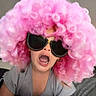child, pink_wig, sunglasses, funny_face, playful, indoor, curly_hair, costume, expression, tshirt, person, portrait, humor, fashion, cute, childhood, casual, home, entertainment, colorful