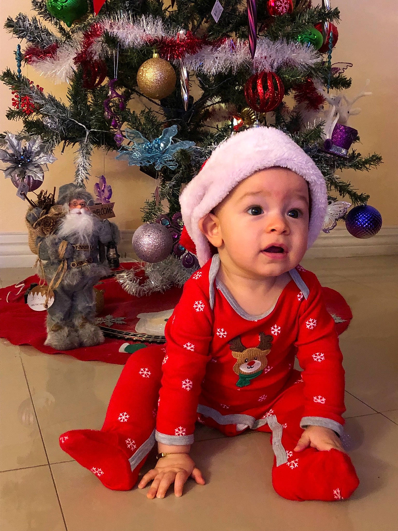 Iker is registered to the contest to win money with this photo: child, christmas, christmas_decoration, christmas_ornament, christmas_tree, event, girl, happiness, headwear, holiday, infant, person, red, skin, smile, toddler, tree