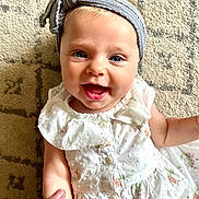 Loretta joined the competition — help win amazing prizes! baby, child, smiling, headband, dress, hand, finger, carpet, pattern, blue_eyes, cute, happy, infant, person, portrait, indoors, skin, clothing, small_child, holding