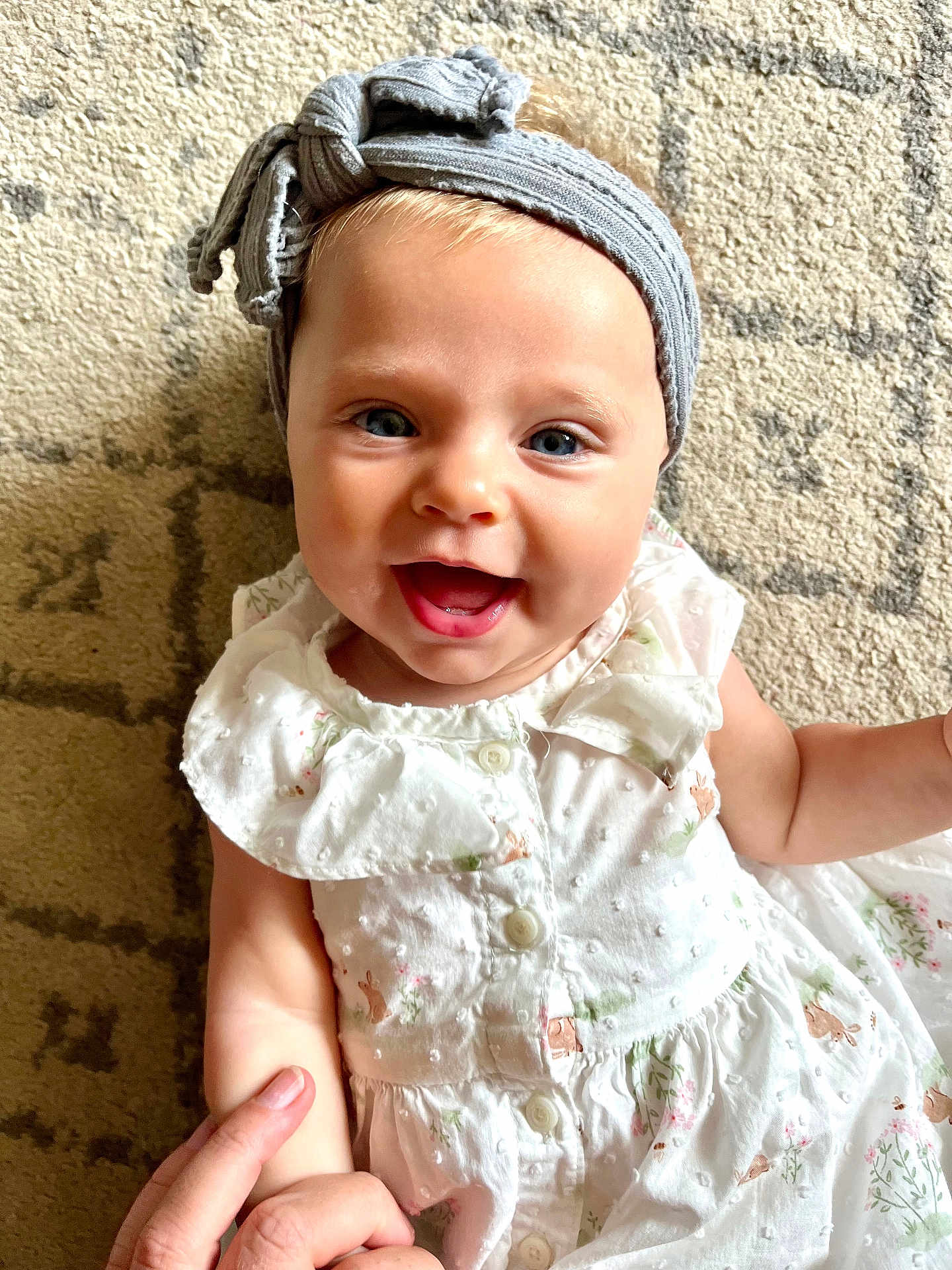 Loretta joined the competition — help win amazing prizes! baby, child, smiling, headband, dress, hand, finger, carpet, pattern, blue_eyes, cute, happy, infant, person, portrait, indoors, skin, clothing, small_child, holding