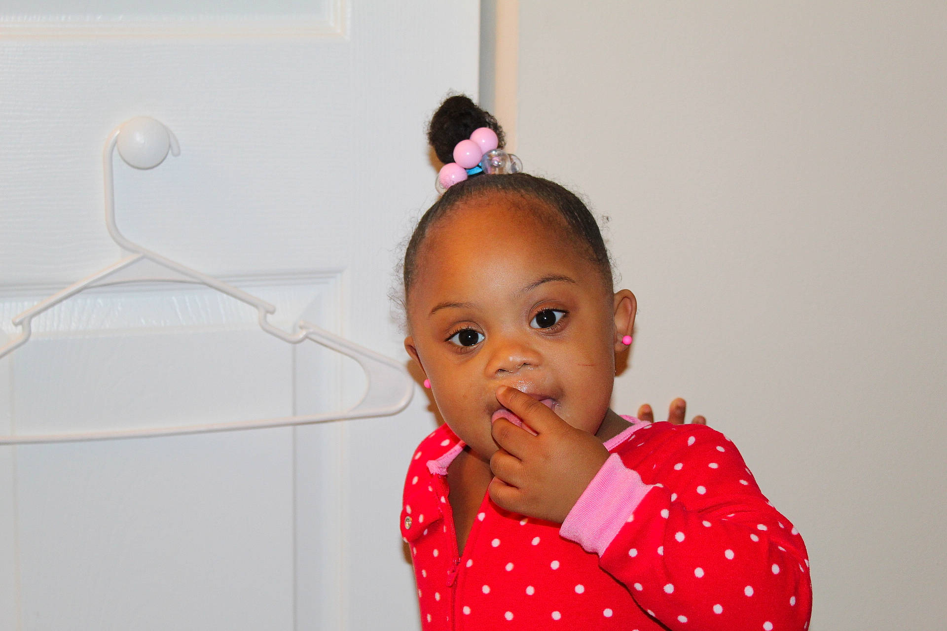 Leah is registered to the contest to win money with this photo: baby, cheek, child, design, ear, face, forehead, hair_accessory, happy, head, lip, neck, nose, person, pink, polka_dot, red, room, skin, standing