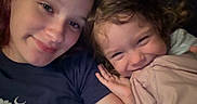 Delilah is registered to the contest to win money with this photo: child, toddler, girl, sibling, selfie, portrait, smiling, sleepy, curly_hair, brown_hair, indoors, snuggling, hugging, close_up, face, pink_clothing, navy_shirt, bed, cozy, family