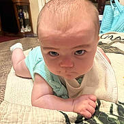 Oaklynn joined the competition — help win amazing prizes! baby, infant, face, expression, determined, lying_down, quilt, blanket, indoor, furniture, carpet, bib, clothing, arm, hand, head, person, closeup, home, soft_lighting