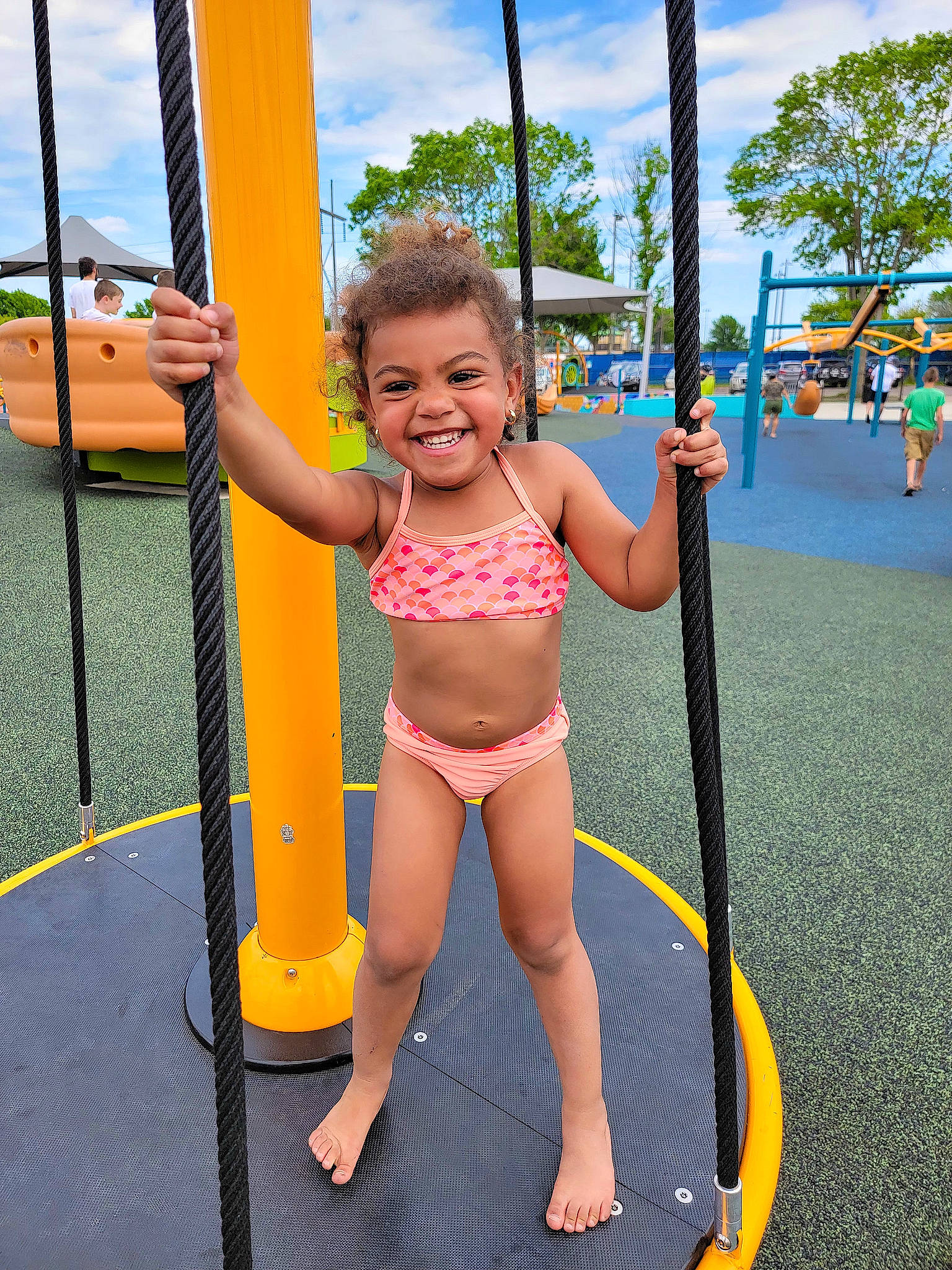 Avayah is registered to the contest to win money with this photo: barefoot, city, cloud, fun, happy, human_leg, human_settlement, joy, leisure, outdoor_play_equipment, person, playground, public_space, recreation, sky, smile, summer, swing, thigh, toddler