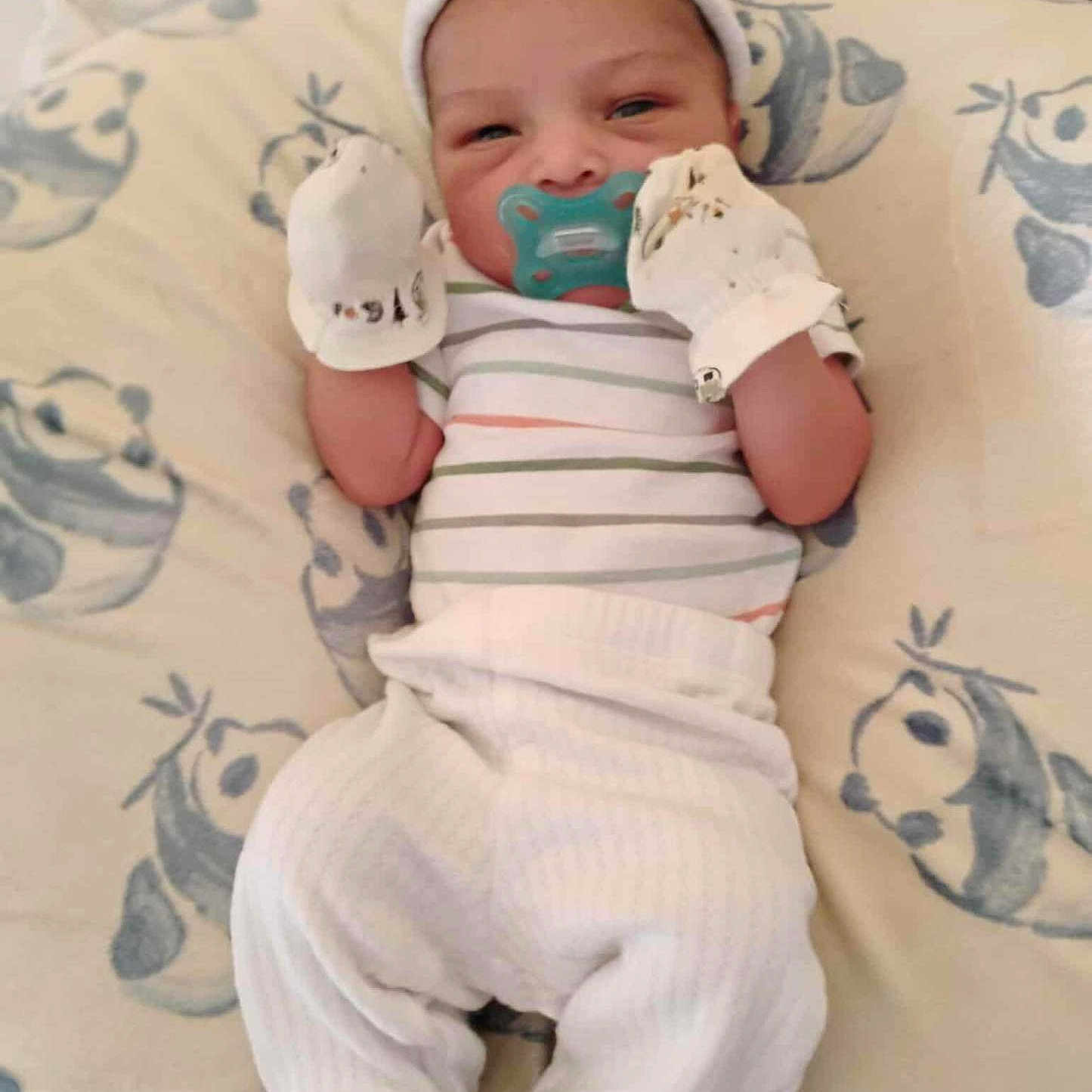 Karson Cain is registered to the contest to win money with this photo: baby, blanket, clothing, cute, cute_baby, hat, indoors, infant, lying_down, mittens, newborn, pacifier, pattern, portrait, resting, sleepy, small_hands, soft, striped_shirt, white_pants