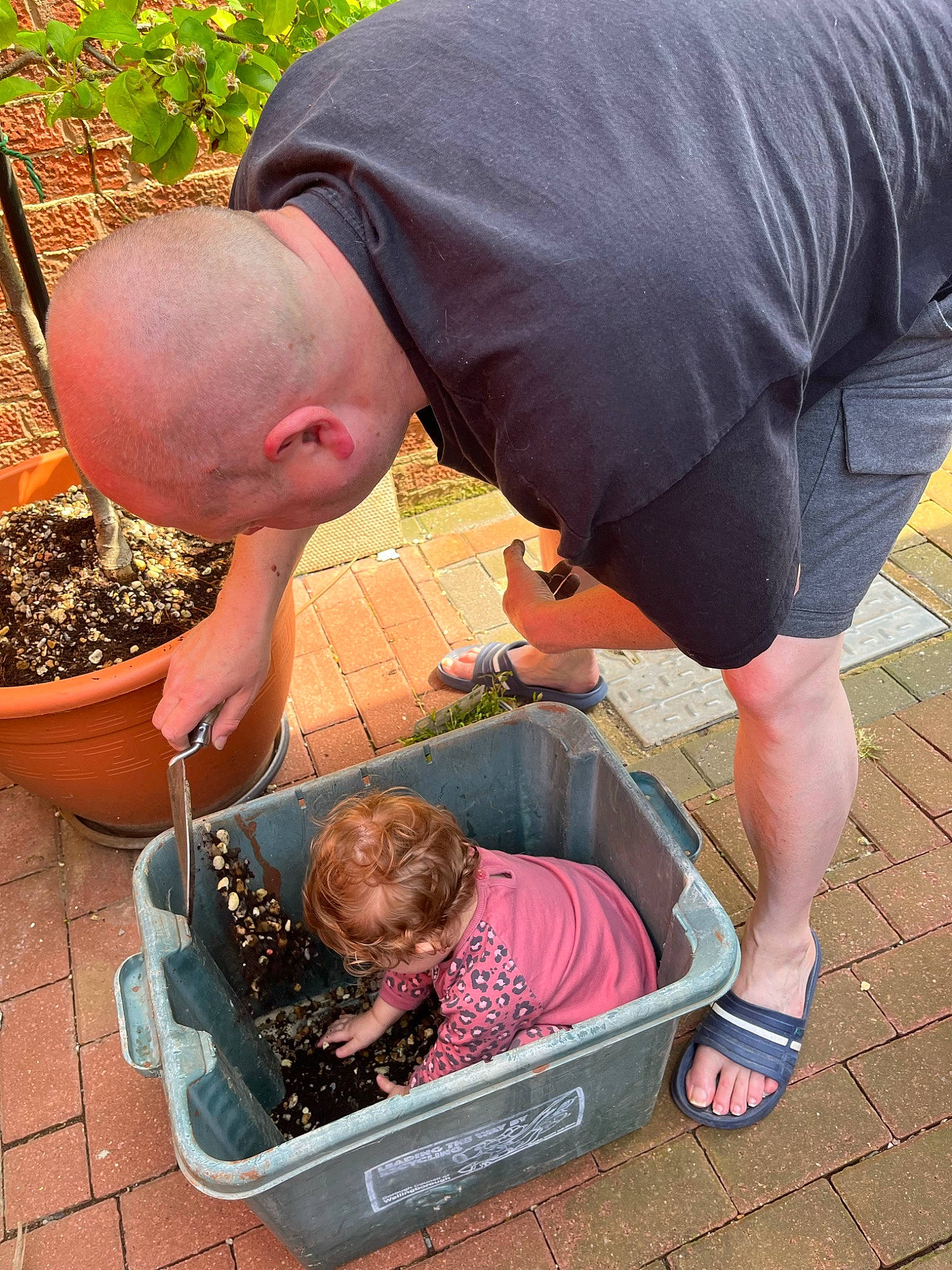 Gracie is registered to the contest to win money with this photo: baby, child, flowerpot, foot, fun, grass, green, hat, human_leg, knee, leisure, person, photograph, plant, red, shorts, sitting, soil, t_shirt, thigh