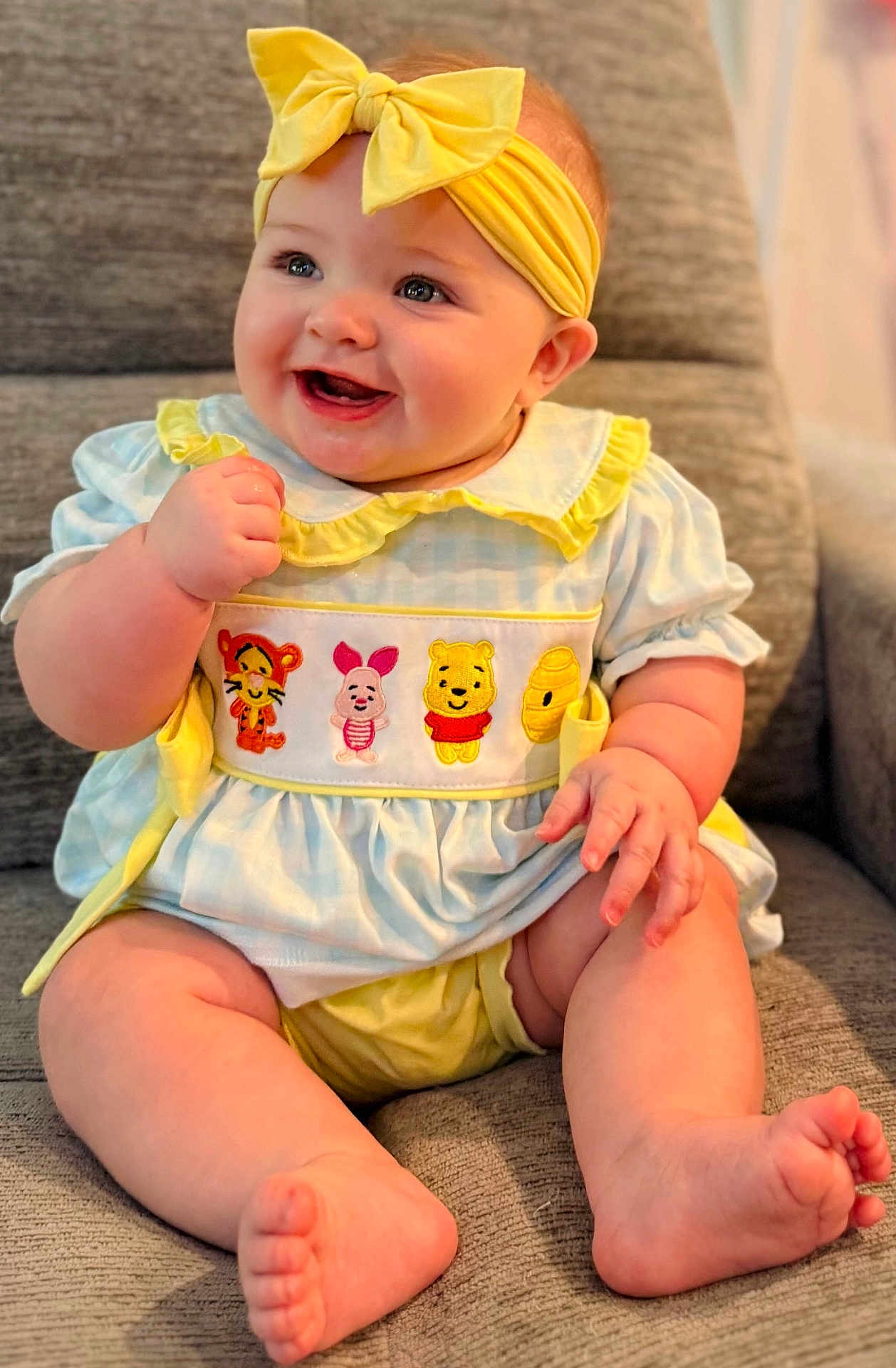 Aria Skye is registered to the contest to win money with this photo: baby, child, smiling, headband, yellow_bow, winnie_the_pooh, tiger, piglet, pooh, honey_pot, blue_dress, yellow_outfit, sitting, barefoot, indoor, cute, happy, chubby_legs, portrait, cozy