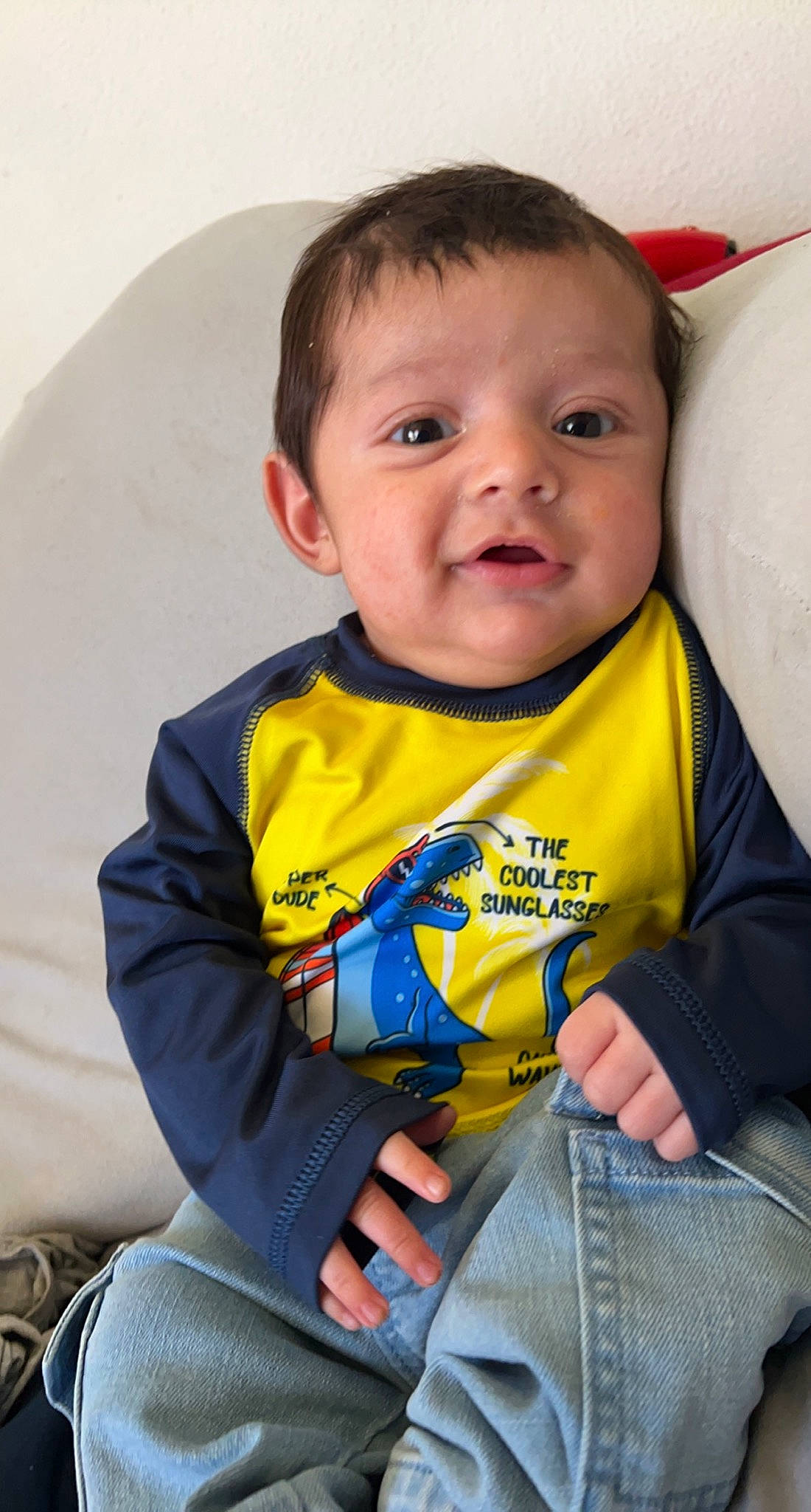 Nico is registered to the contest to win money with this photo: arm, baby, baby_toddler_clothing, cheek, chin, comfort, eye, facial_expression, finger, hairstyle, hand, happy, head, human_body, iris, nose, person, skin, sleeve, smile