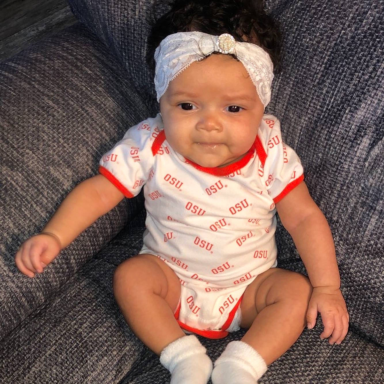 Novalee is registered to the contest to win money with this photo: baby, baby_products, baby_toddler_clothing, cheek, child, eye, face, fashion_accessory, finger, hair_accessory, hand, head, headgear, headwear, iris, lip, person, product, sitting, skin