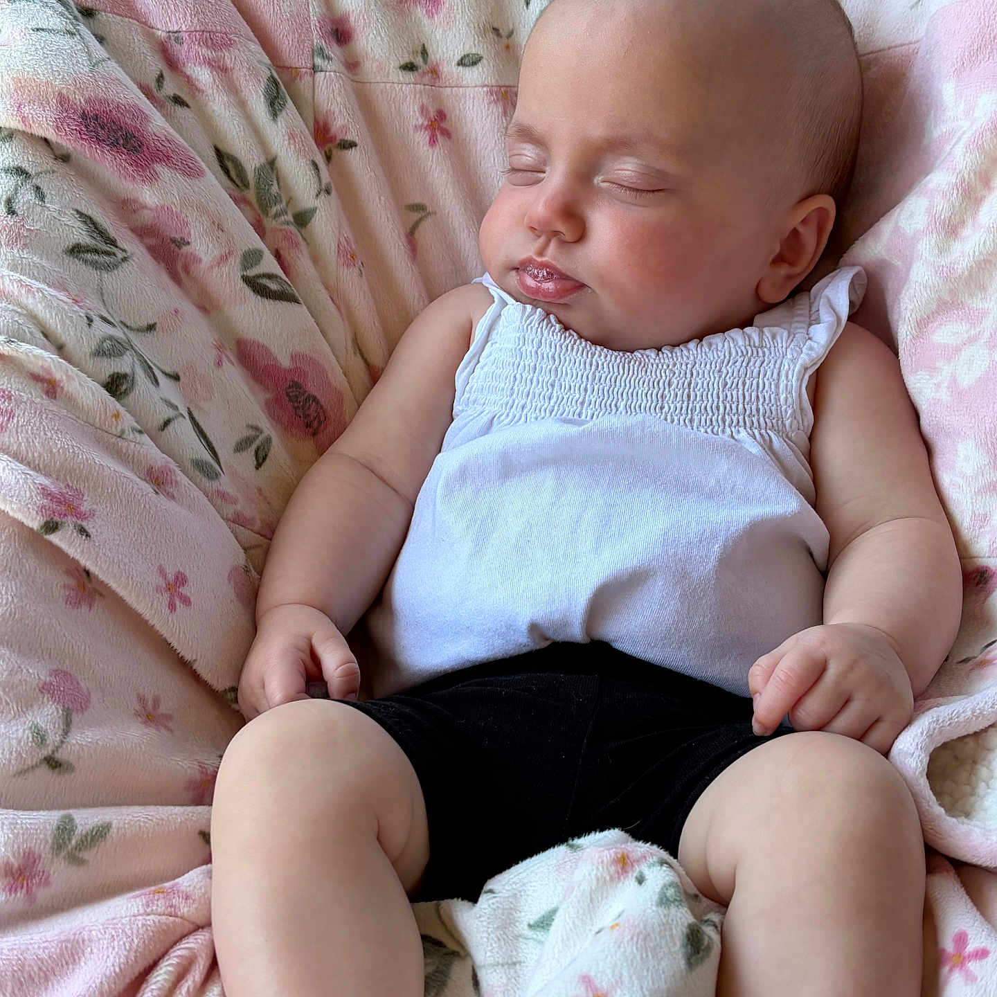 Arisa is registered to the contest to win money with this photo: baby, sleeping, blanket, floral_pattern, white_top, black_shorts, infant, peaceful, soft_texture, cute, resting, child, small_hands, chubby_legs, indoors, portrait, relaxation, comfort, nap, closeup