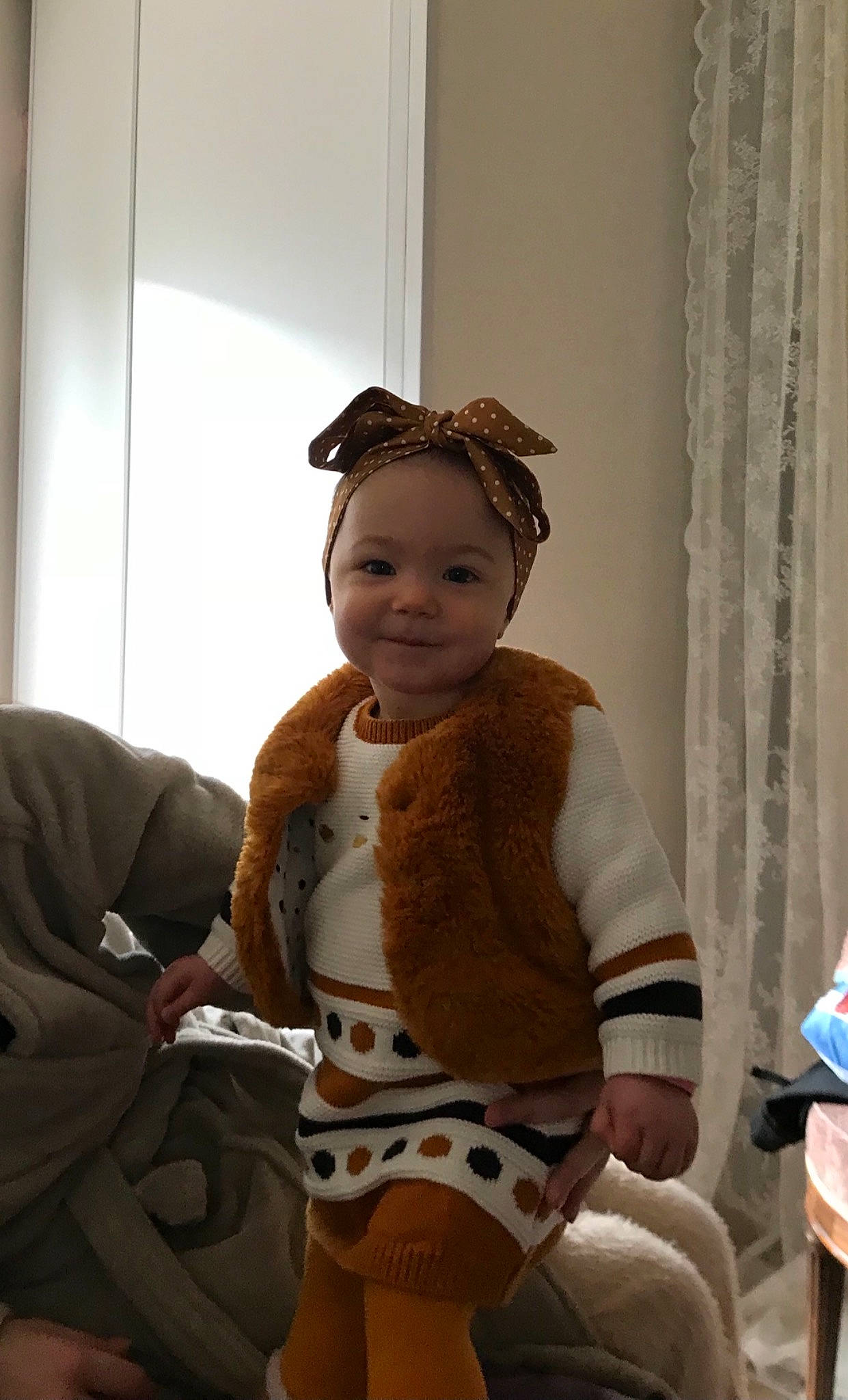 Laïna participe au concours pour gagner de l'argent avec cette photo : baby, baby_laughing, baby_products, baby_toddler_clothing, bonnet, comfort, costume_accessory, curtain, fur, hair_accessory, headband, headpiece, joy, person, sock, textile, window_treatment