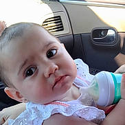 Angelina joined the competition — help win amazing prizes! baby, child, bottle, car_interior, white_clothing, pink_hair_accessory, face, hand, infant, portrait, seatbelt, window, door_handle, curious, young_child, cute, skin, eyes, sitting, feeding
