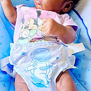 Korriana is registered to the contest to win money with this photo: baby, infant, child, mickey_mouse, minnie_mouse, diaper, astronaut, space_theme, baby_seat, socks, curly_hair, cute, portrait, looking_away, indoor, blue, pink, clothing, relaxed, young