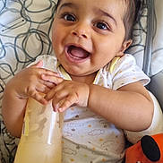 Liam a rejoint le concours — aidez-le/la à gagner de superbes lots ! baby, bottle, high_chair, chicco, clothing, happy, smiling, infant, child, hand, face, feeding, seat, toy, orange, black, white, patterned, cute, indoors