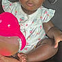 toddler, child, car_seat, sippy_cup, pink, white_clothing, ice_cream_pattern, cherry_pattern, curly_hair, barefoot, indoors, seat_belt, person, cute, baby, young_child, skin, face, eyes, hand