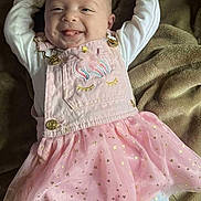 Kadence is registered to the contest to win money with this photo: baby, child, smiling, pink_dress, tutu, star_pattern, long_sleeve_shirt, blanket, happy, tongue_out, cute, infant, face, person, lying_down, cozy, soft, golden_buttons, head, playful