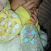 Kaleo is registered to the contest to win money with this photo: baby, infant, bottle, blanket, onesie, hand, face, sleeping, cozy, cute, yellow, pattern, fingers, soft, child, newborn, indoor, warm, comfort, clothing