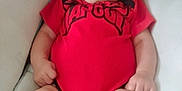 Kaleo is registered to the contest to win money with this photo: baby, child, closeup, comfort, cushion, expression, face, foot, hand, hat, headwear, indoor, infant, legs, person, red_clothing, skin, soft_toy, sombrero, toy