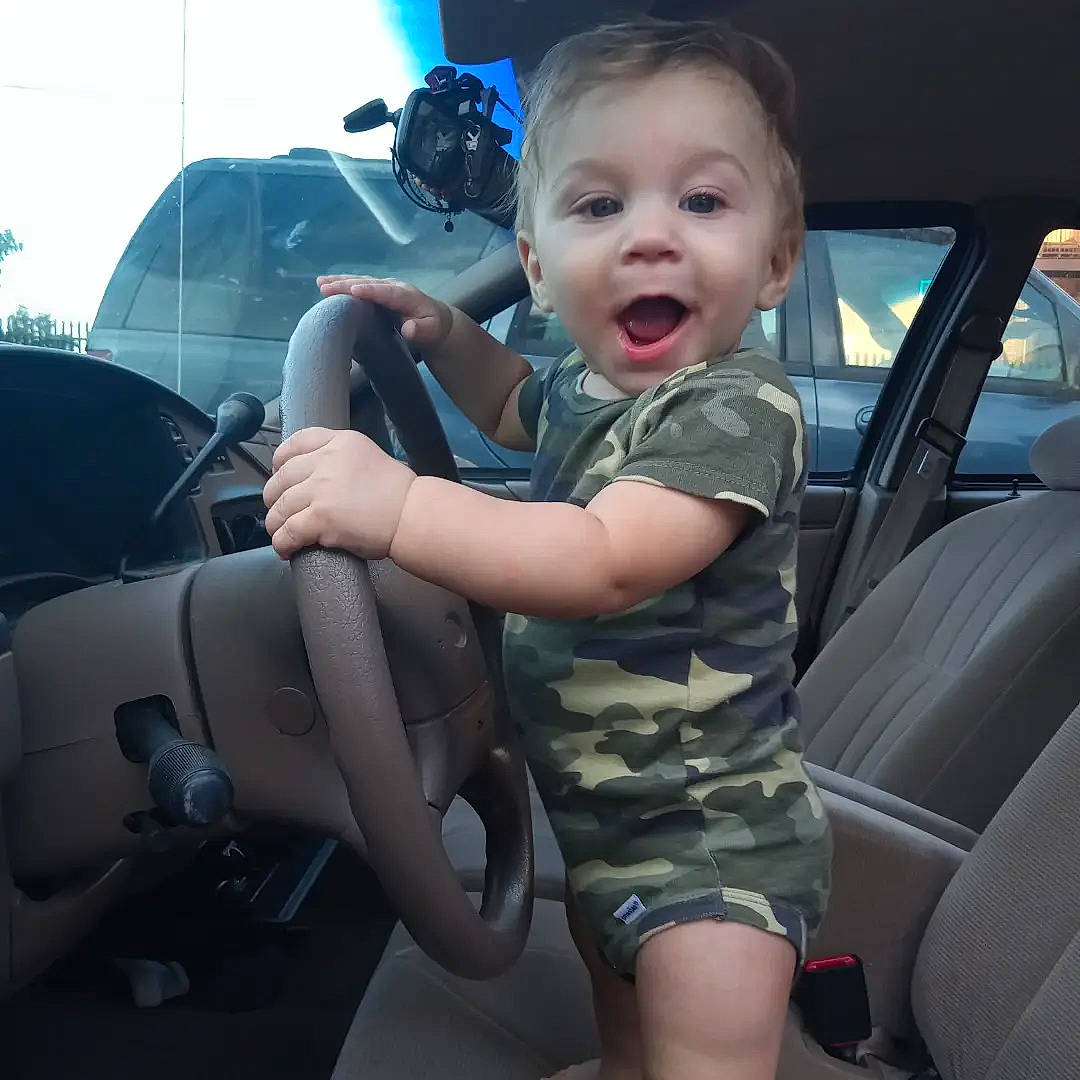Joey is registered to the contest to win money with this photo: auto_part, automotive_design, automotive_exterior, car, car_seat, car_seat_cover, face, gesture, happy, head_restraint, hood, mode_of_transport, motor_vehicle, person, personal_luxury_car, smile, steering_wheel, surprise, toddler, vehicle