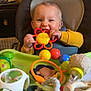 Jules participe au concours pour gagner de l'argent avec cette photo : baby, blue, child, colorful, cute, face, feeding_chair, green, happy, high_chair, indoors, infant, kitchen, orange, plastic_toy, playtime, red, smiling, toy, yellow