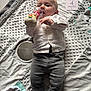 Jules participe au concours pour gagner de l'argent avec cette photo : baby, baby_toy, blanket, car_pattern, card, clothing, curious_expression, cute, face, floor, grey_pants, indoor, infant, lying_down, milestone, person, socks, soft_texture, toy, white_shirt