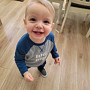Spencer is registered to the contest to win money with this photo: big_bro, blue_sleeves, casual_clothing, chair, child, cute, flooring, furniture, happy, home, indoor, person, pet_crate, portrait, shirt, smiling, standing, toddler, wooden_floor, young_child