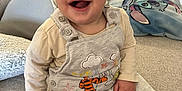 Raphaël a rejoint le concours — aidez-le/la à gagner de superbes lots ! baby, smiling, sitting, indoors, couch, overalls, cartoon, pillow, happy, child, face, clothing, home, furniture, cute, infant, person, expression, cozy, warm