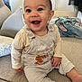 baby, smiling, sitting, indoors, couch, overalls, cartoon, pillow, happy, child, face, clothing, home, furniture, cute, infant, person, expression, cozy, warm