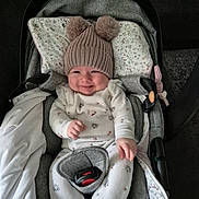 Célia a rejoint le concours — aidez-le/la à gagner de superbes lots ! baby, smiling, hat, pom_poms, car_seat, onesie, infant, cute, cozy, child, happy, indoor, blanket, clothing, seatbelt, comfort, portrait, person, headwear, warm