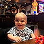 baby, background, chandelier, child, clothing, cute, decor, face, furniture, happy, indoor, lighting, motorcycle, person, restaurant, seat, smiling, table, toy, wood