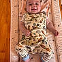 Otto is registered to the contest to win money with this photo: baby, smiling, infant, changing_pad, patterned_clothing, dragons, rockets, teddy_bears, wooden_table, pink_blanket, cute, happy, lying_down, child, indoors, foot, hand, playful, soft_lighting, portrait