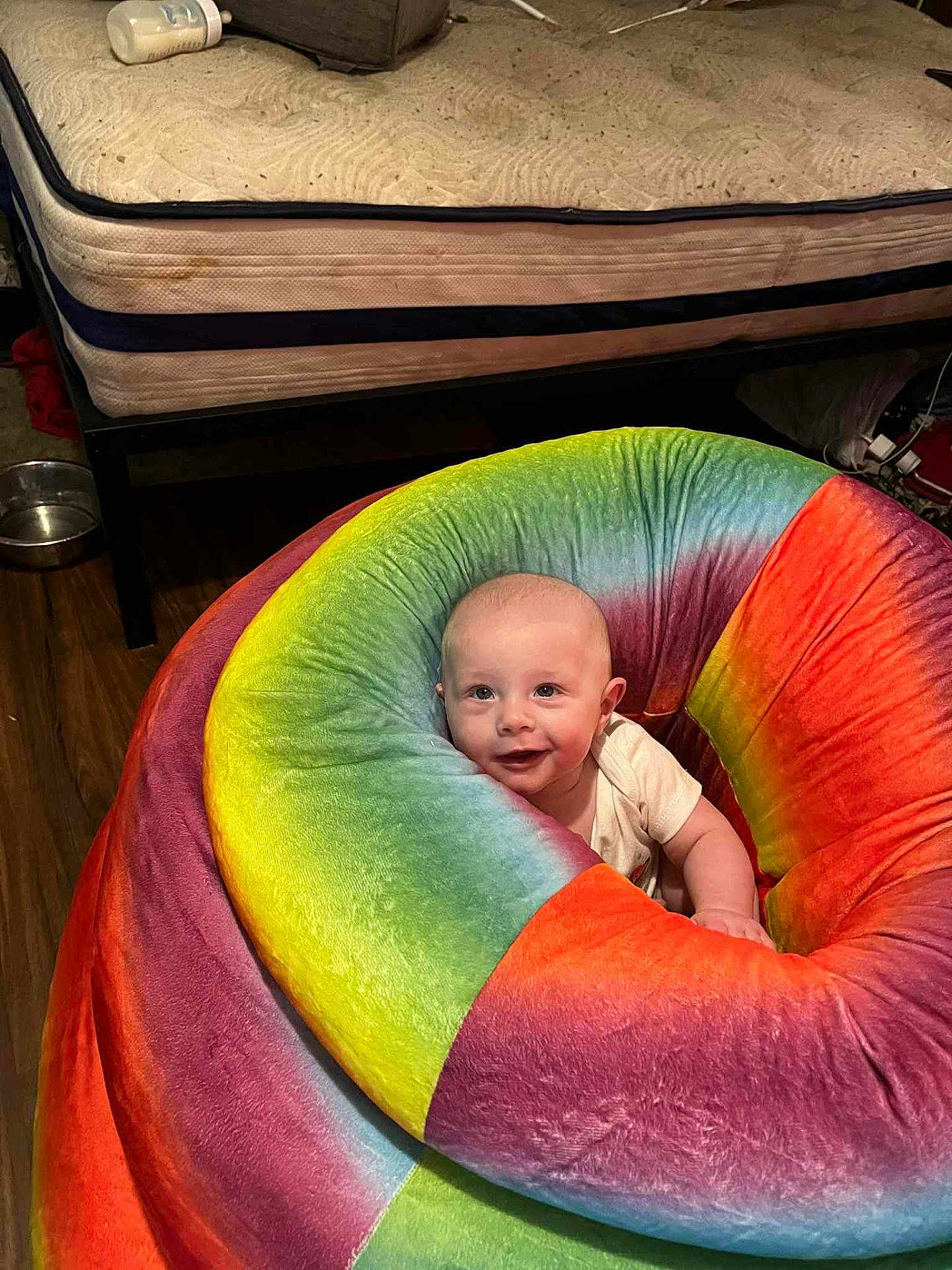 Malachi Swartz joined the competition — help win amazing prizes! baby, infant, beanbag, colorful, rainbow, smiling, indoor, mattress, floor, wooden_floor, furniture, cozy, child, cute, happy, person, seat, plush, home, relaxation