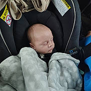 Artemas is registered to the contest to win money with this photo: baby, infant, newborn, sleeping_baby, car_seat, blanket, harness, headrest, fabric, soft_texture, warning_label, cozy, child, face, peaceful, portrait, inside_vehicle, seat_belt, clothing, car_accessory