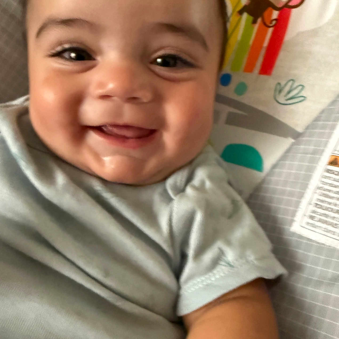 Aurelio is registered to the contest to win money with this photo: baby, blanket, cartoon, cheeks, child, closeup, clothing, cute, eyelashes, face, happy, indoors, infant, monkey, pattern, portrait, rainbow, skin, smiling, toddler