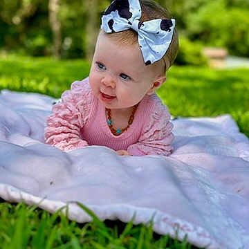 Kennzie joined the competition — help win amazing prizes! baby, child, infant, bow, headband, pink_clothing, blanket, grass, outdoor, nature, greenery, smile, cute, portrait, young_child, playful, sunlight, park, head, face