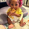 baby, child, infant, bonnet, yellow_clothing, ice_cream_cone, play_mat, barefoot, cute, indoor, smiling, sitting, hands, face, headwear, cheerful, soft_toys, colorful, skin, portrait