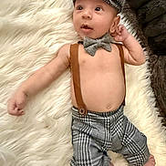 Maddox is registered to the contest to win money with this photo: baby, infant, boy, clothing, hat, bow_tie, suspenders, plaid, pants, bare_chest, rug, fur_rug, lying_down, cute, face, expression, indoor, soft_texture, child, portrait