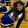 activity, athlete, blue, cheerleader, child, dance, gym_floor, happy, indoor, long_hair, people, performance, posing, smile, sport, team, uniform, white, wood_floor, young_girl