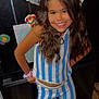 Lyric is registered to the contest to win money with this photo: child, girl, smiling, striped_clothing, long_hair, wavy_hair, fridge, drawings, colorful, wooden_floor, scrunchie, posing, indoors, happy, person, clothing, pants, top, home, artwork