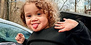 Lydiah is registered to the contest to win money with this photo: autumn, black_sweater, car, child, curly_hair, cute, expression, face, fall, hand_wave, nature, outdoor, person, playful, portrait, smile, toddler, tongue_out, trees, young_child