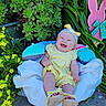 Katrena is registered to the contest to win money with this photo: baby, smiling, yellow_dress, headband, blanket, outdoor, plants, flowers, greenery, pink_bunny, happy, cute, infant, footwear, sandals, nature, sunlight, garden, portrait, child