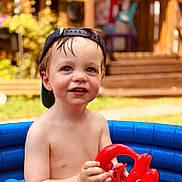 Noam a rejoint le concours — aidez-le/la à gagner de superbes lots ! backward_hat, bare_chest, boy, cap, child, daylight, fish_toy, garden, happy, inflatable_pool, outdoor, playing, pool, red_toy, skin, smiling, summer, toddler, toy, water