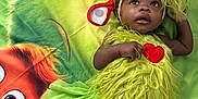 Rain joined the competition — help win amazing prizes! baby, child, costume, green, grinch, blanket, fur, cute, lying_down, floor, headband, expression, portrait, indoor, holiday, character, red_heart, curious, wide_eyes, soft_texture