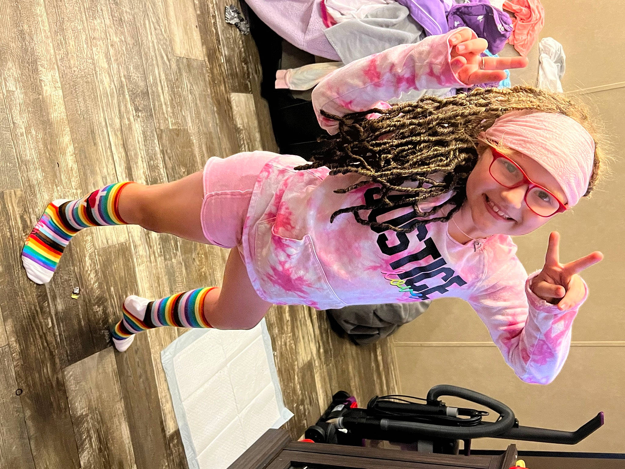 Adalynn is registered to the contest to win money with this photo: arm, bangs, child, cool, entertainment, event, eyewear, fun, hand, happy, headwear, human_body, human_leg, joy, knee, magenta, pattern, person, pink, sock