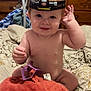 Carter is registered to the contest to win money with this photo: baby, child, headlamp, plush, toy, bed, blanket, furniture, wood, hair_clip, smile, indoors, cute, sitting, face, skin, expression, orange, purple, comfort