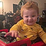 Carter joined the competition — help win amazing prizes! toddler, child, red_hair, yellow_shirt, toy_car, indoor, smiling, playful, curly_hair, person, young_child, furniture, warm_lighting, home, seat, hand, face, vehicle_print, cozy, baby